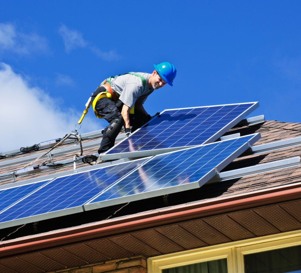 Worker installing solar panels on a residential roof